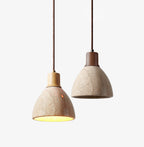 Two Clérachic travertine dome pendants side by side on a white backdrop, one with a pale wood collar and one with a dark walnut collar.