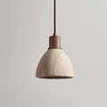 This Clérachic pendant with a dark walnut collar unlit on a plain greige backdrop, the pitted travertine dome seen from the side.