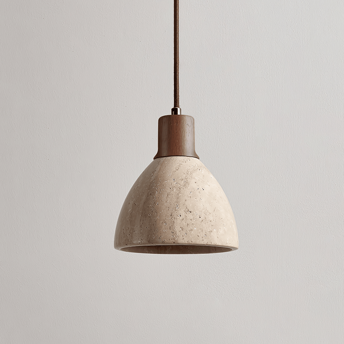 This Clérachic pendant with a dark walnut collar unlit on a plain greige backdrop, the pitted travertine dome seen from the side.