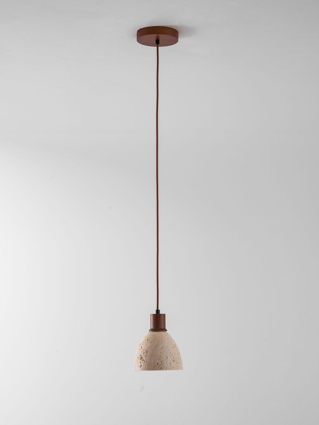 A single Clérachic pendant on a dark ceiling canopy and a long cord, hung against a plain pale grey backdrop.