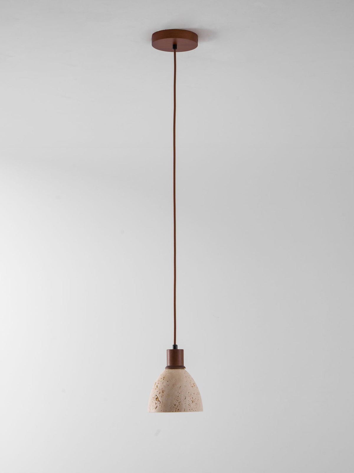 A single Clérachic pendant on a dark ceiling canopy and a long cord, hung against a plain pale grey backdrop.