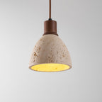 Close view of the pitted travertine dome and dark walnut collar of this Clérachic pendant, the inner surface glowing yellow.