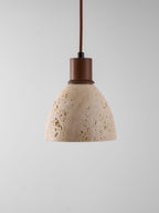 This Clérachic pendant unlit against a grey backdrop, showing the natural pores and veining of the travertine dome and the walnut collar.
