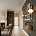 Clérachic globe wall lights lit along a hallway with green patterned wallpaper, framed photographs and woven baskets on hooks.