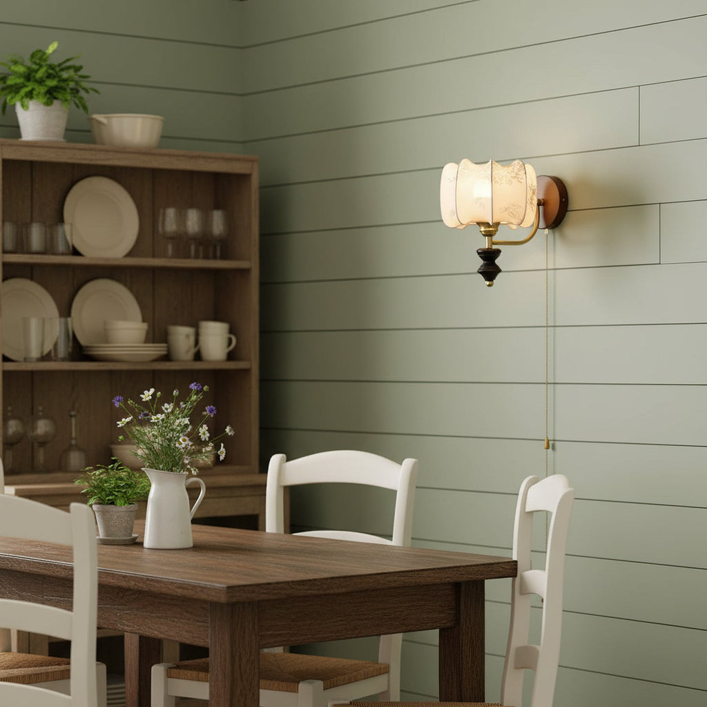 Clérachic wall light with a printed drum shade on a sage-green shiplap wall, above a dining table and a shelf of crockery.