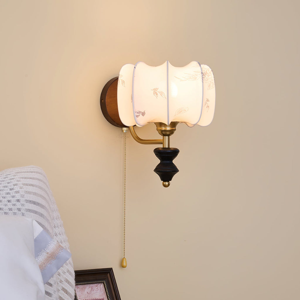 Clérachic wall light with a drum-shaped printed fabric shade and a pull chain, above a framed picture and a striped blanket.