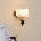 Clérachic wall light with a drum-shaped printed fabric shade and a pull chain, above a framed picture and a striped blanket.