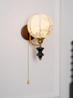 Clérachic globe wall light with a floral-printed shade, seen from a slight angle against a white panelled wall.