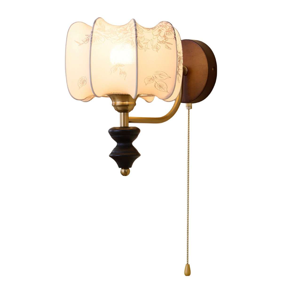 Clérachic wall light with a lit drum shade, a brass arm and a pull chain, on a plain white backdrop.