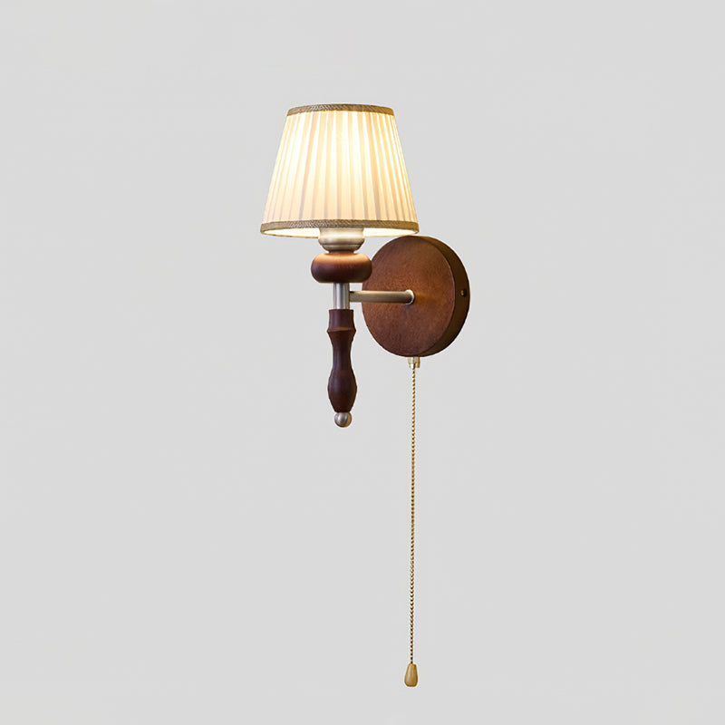 Clérachic wall light with a pleated white shade and a dark wood stem, on a plain grey backdrop.