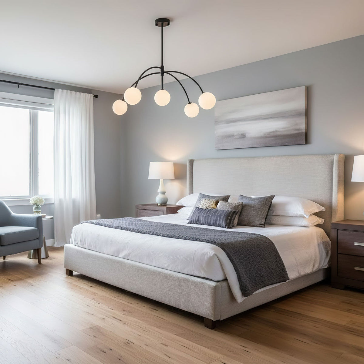 In a bedroom with grey walls and a low upholstered bed, a black Clérachic chandelier lights five round white globes.