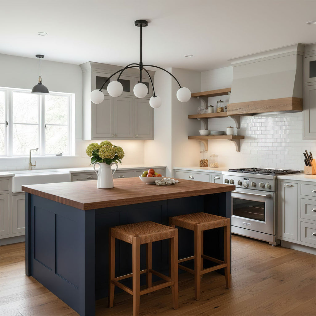 This black Clérachic chandelier hangs in a kitchen with grey cabinets, open wooden shelves and a navy island with a butcher-block top.