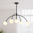 Seen from below, a black Clérachic chandelier with five frosted globes on curved arms, in a bright room with sheer curtains.