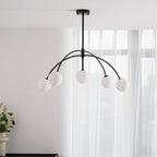Slightly from below, a black Clérachic chandelier with five milky globes hangs against sheer white curtains, switched off.