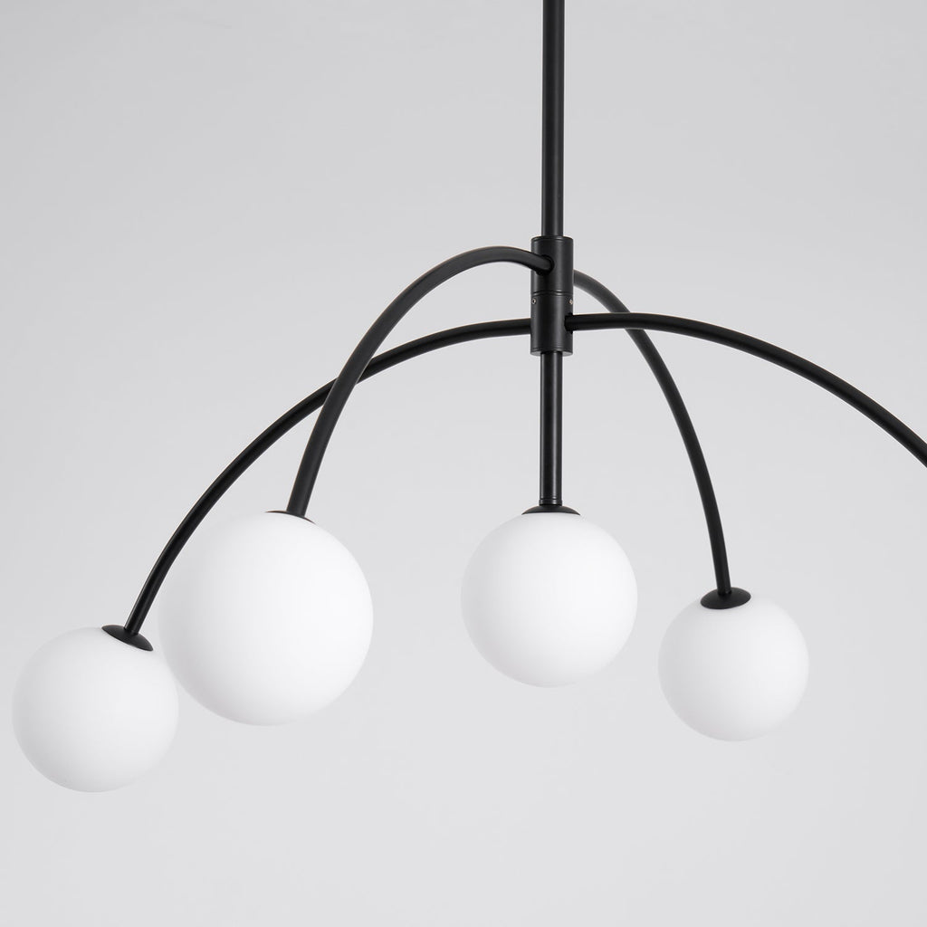 Close view of four frosted globes on curved black arms, joined at a black collar on the central rod of this Clérachic chandelier.