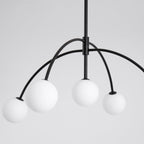 Close view of four frosted globes on curved black arms, joined at a black collar on the central rod of this Clérachic chandelier.