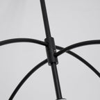 Close view of the black collar where the curved arms meet the central rod of this Clérachic chandelier, on a pale grey backdrop.