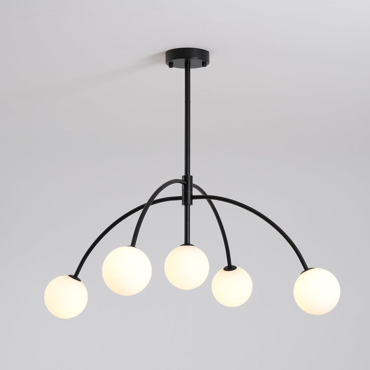 Five lit globes glow warm on this black Clérachic chandelier, shown against a pale grey backdrop.