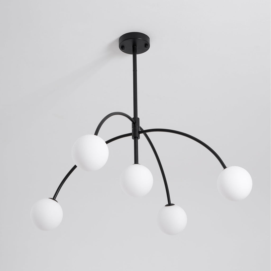 This Clérachic chandelier, switched off, has five white globes on arched black arms under a round ceiling canopy, on pale grey.