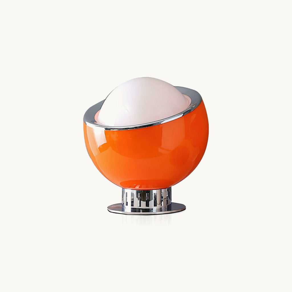 Orange glass sphere with a chrome rim and a white dome on top, raised on a chrome pedestal, shown on a plain off-white backdrop for this Clérachic table lamp.