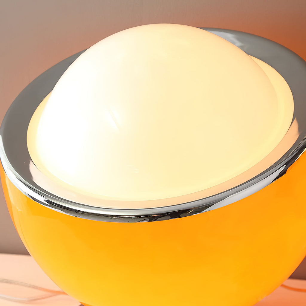 Close view of the white glass dome, polished chrome rim and glossy amber-yellow body of this Clérachic table lamp, glowing from within.