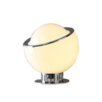 Lit from within, the white version of this Clérachic table lamp shows a warm cream glow through the globe, with a chrome rim and base.