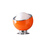 Smaller orange table lamp from Clérachic with a white dome, chrome rim and a short chrome stand on a round plate.
