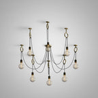 The nine-head layout of this Clérachic pendant on a pale grey backdrop, each cable looped through a copper ring above its own bulb.