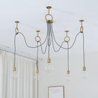 Looking up at five clear globe bulbs on black cables looped through copper rings, in front of a white curtain, on this Clérachic pendant.