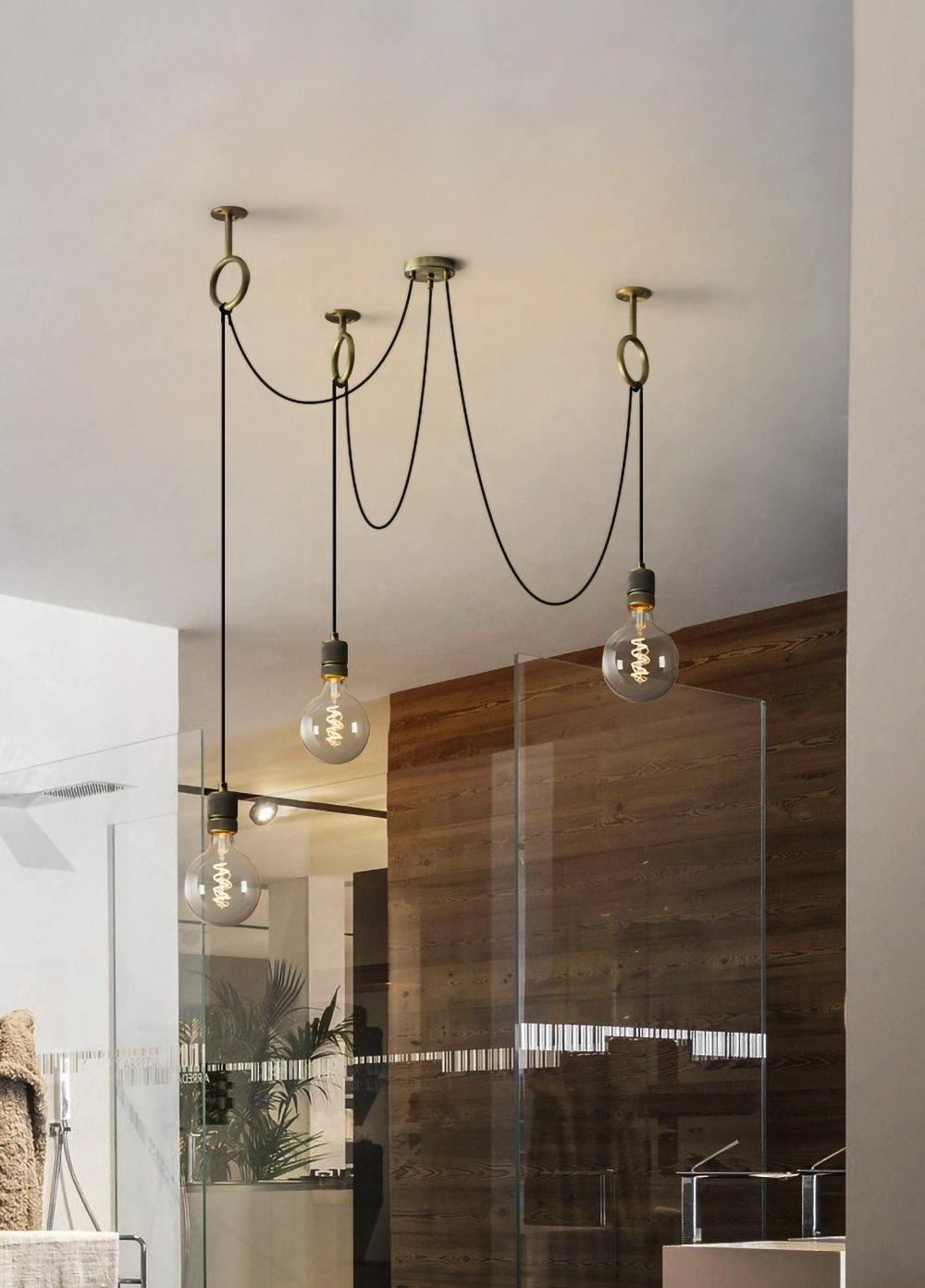 Bulbs of this Clérachic pendant hang in a bright bathroom-style space with a glass screen and a warm timber wall.