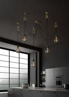Against a charcoal wall in a dark kitchen with a large black-framed window, this Clérachic pendant hangs five globe bulbs at varied heights.