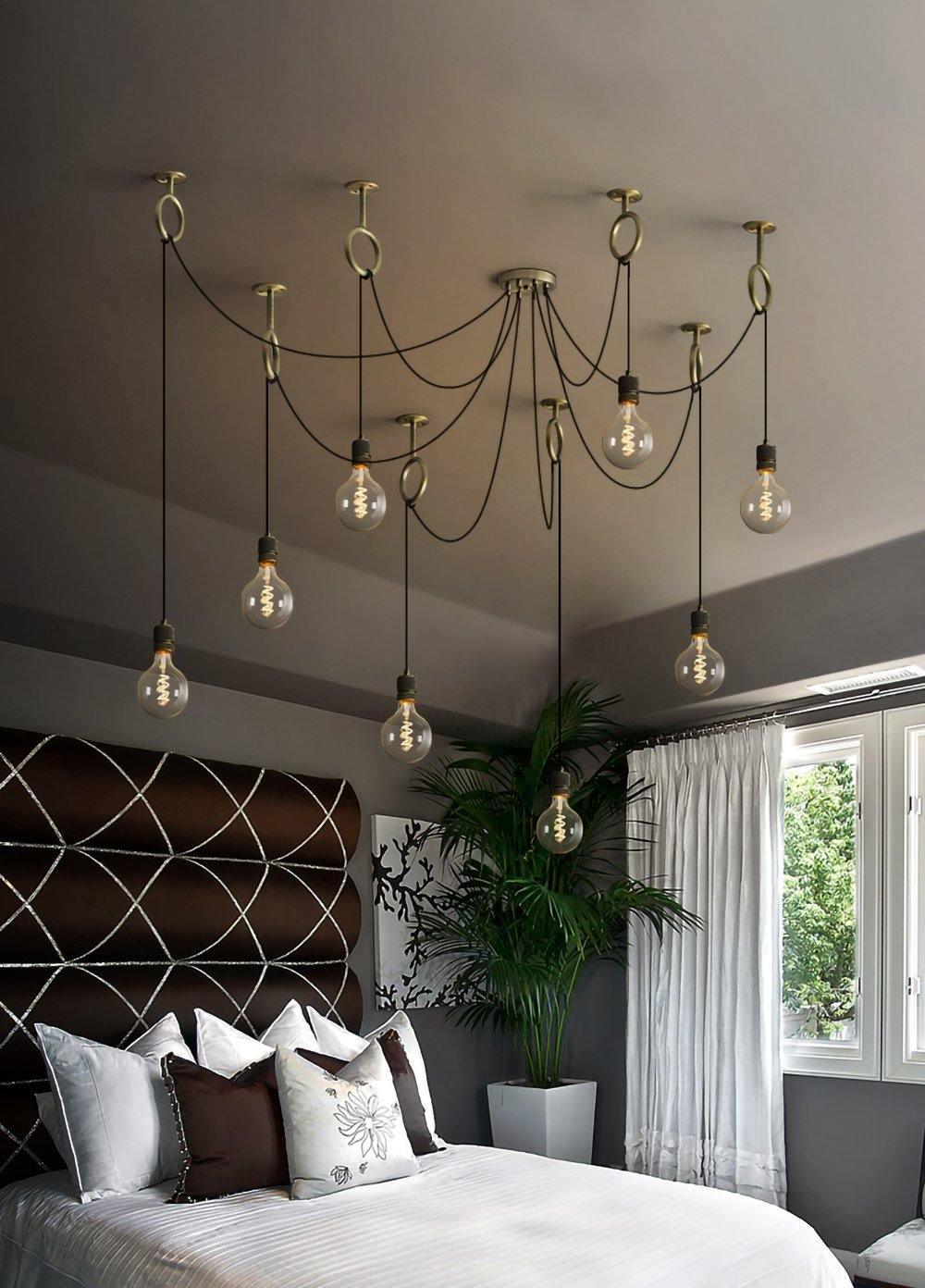 Warmly lit globe bulbs hang over a bed with a patterned brown headboard and white linen, from this Clérachic pendant.