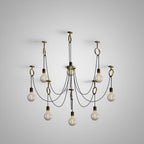 Nine amber-glass globe bulbs on black cables hang below copper hook rings in a fan, shown for this Clérachic pendant on a grey studio backdrop.
