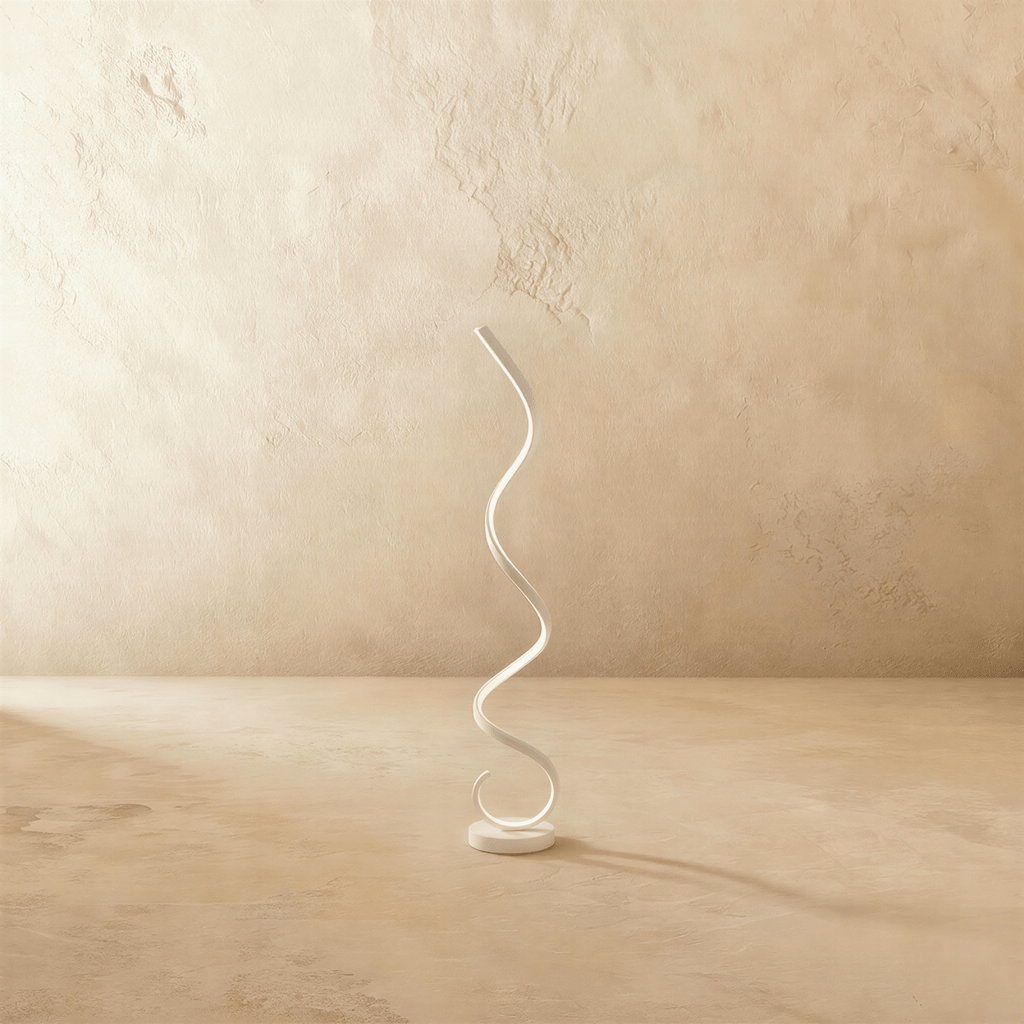 Clérachic white spiral LED floor lamp, a single ribbon curling up from a round base, on a limewash floor and wall.