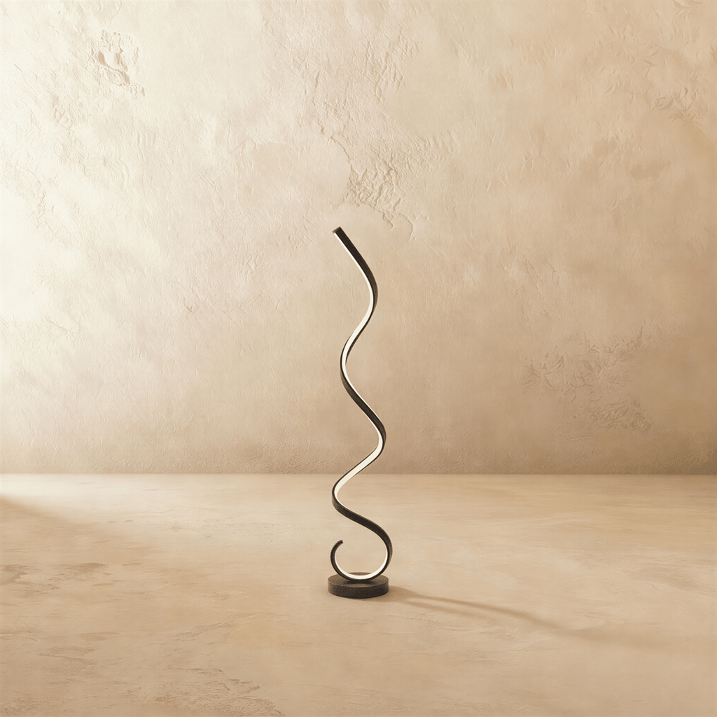 Clérachic black spiral LED floor lamp, a glowing ribbon rising in curves from a round black base against limewash.