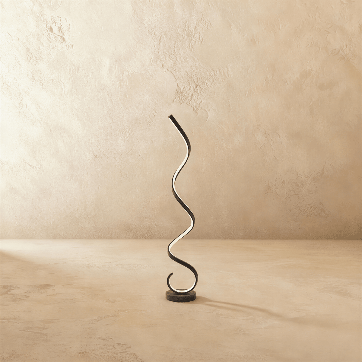 Clérachic black spiral LED floor lamp, a glowing ribbon rising in curves from a round black base against limewash.