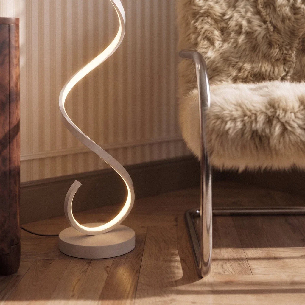 Clérachic white spiral floor lamp base close up, a lit LED ribbon curling from a round disc on a herringbone wood floor.