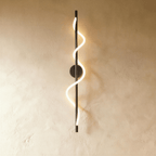 Clérachic slim vertical black wall light with a spiralling glowing LED strip, on a warm limewash wall.