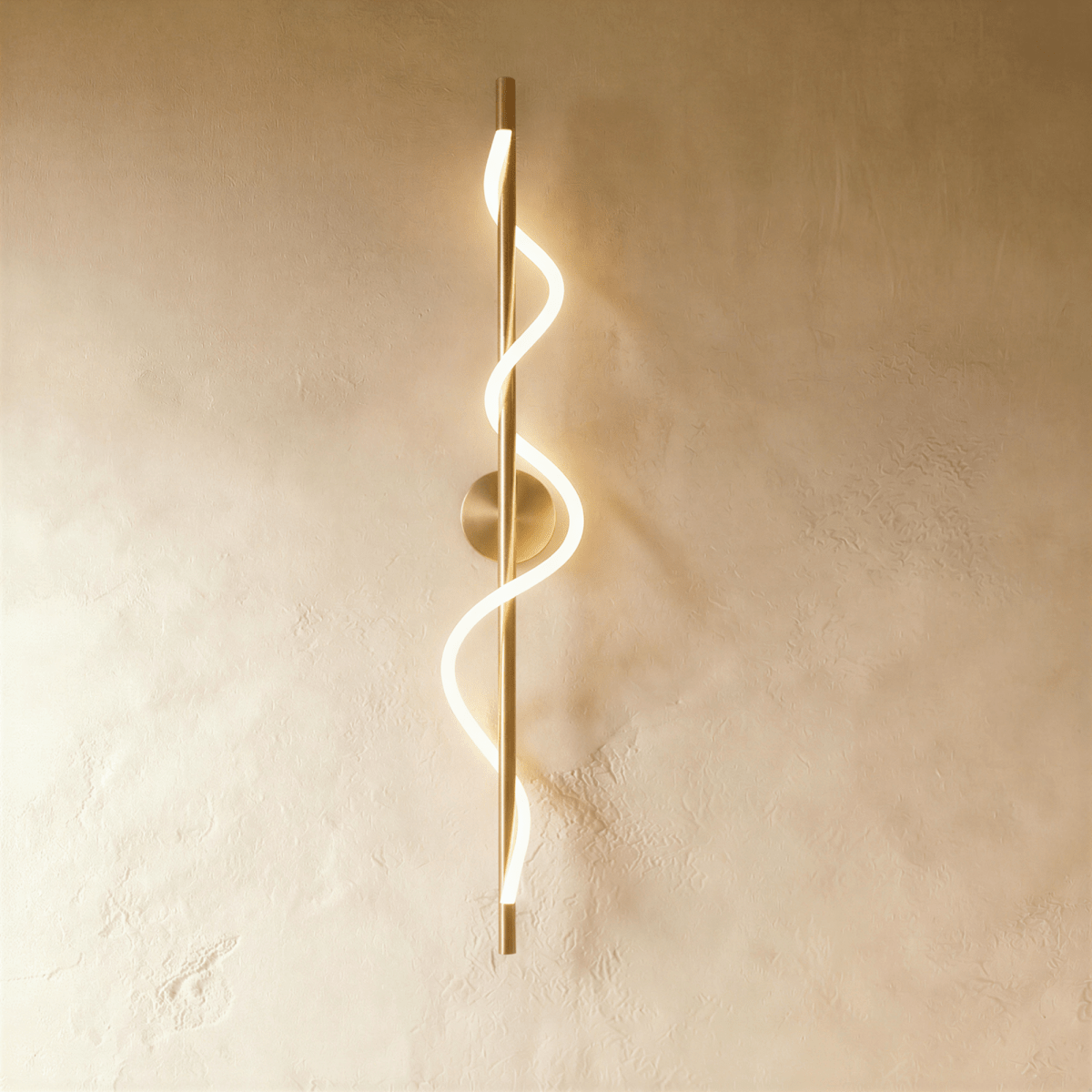 Clérachic slim vertical brass wall light with a glowing spiral LED strip winding round its rod, on a warm limewash wall.
