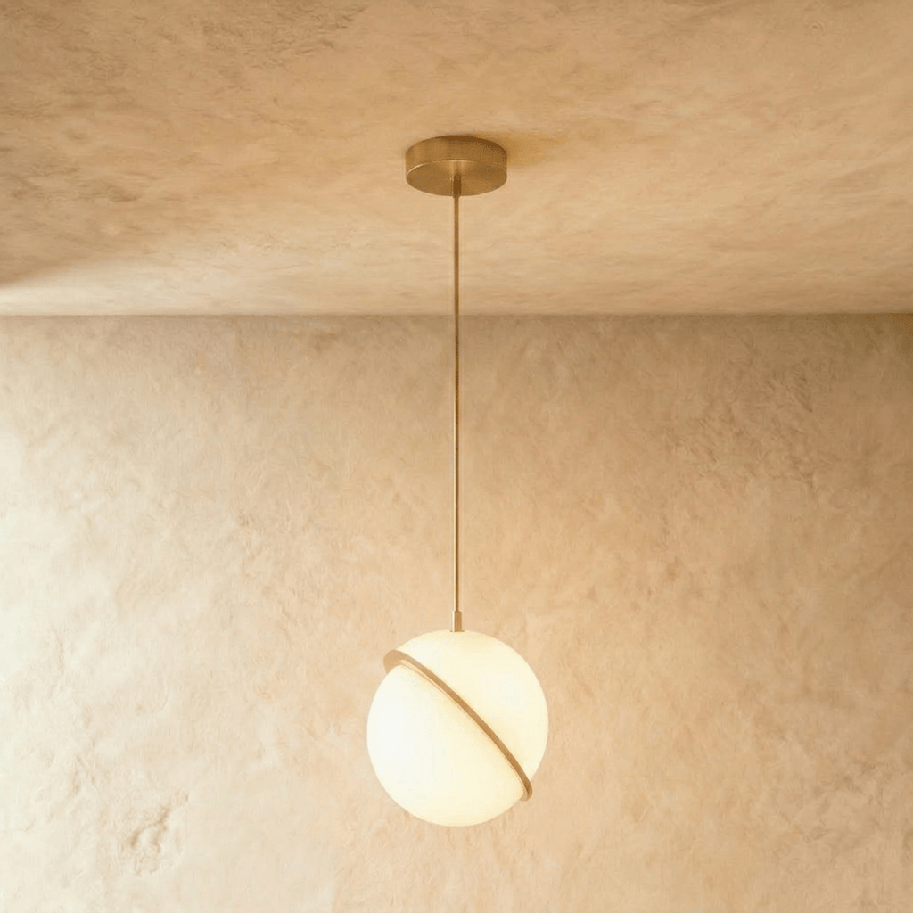 Clérachic largest opal white sphere pendant in the set, a tilted brass-finish ring across the globe, hung on a brass rod.
