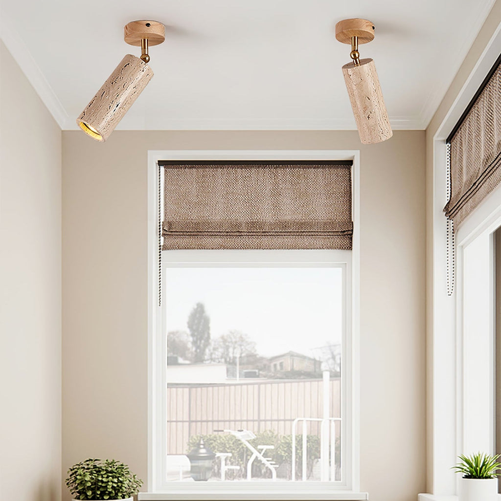Two Clérachic travertine spotlights with light wood canopies on a white ceiling above a window with a woven roman blind.