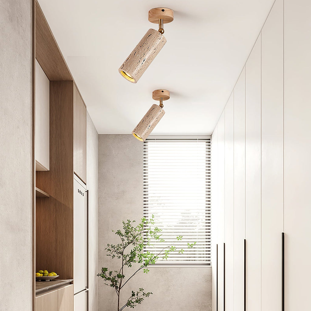 A pair of Clérachic stone cylinder spotlights angled down in a narrow kitchen corridor, with walnut shelving, a window and white cabinet doors.