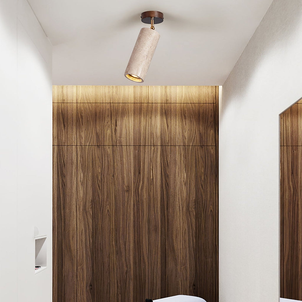 This Clérachic stone spotlight hangs from a white ceiling above a walnut wall panel that is lit with a soft strip of warm light.