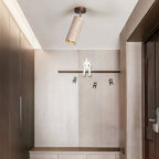 Clérachic travertine spotlight on the ceiling of an entrance hall, with a pale stone wall, wall hooks and wooden cabinets on both sides.