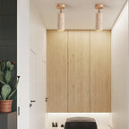 Two Clérachic travertine spotlights with light wood canopies on a ceiling above pale timber panelling and a dark low bench.