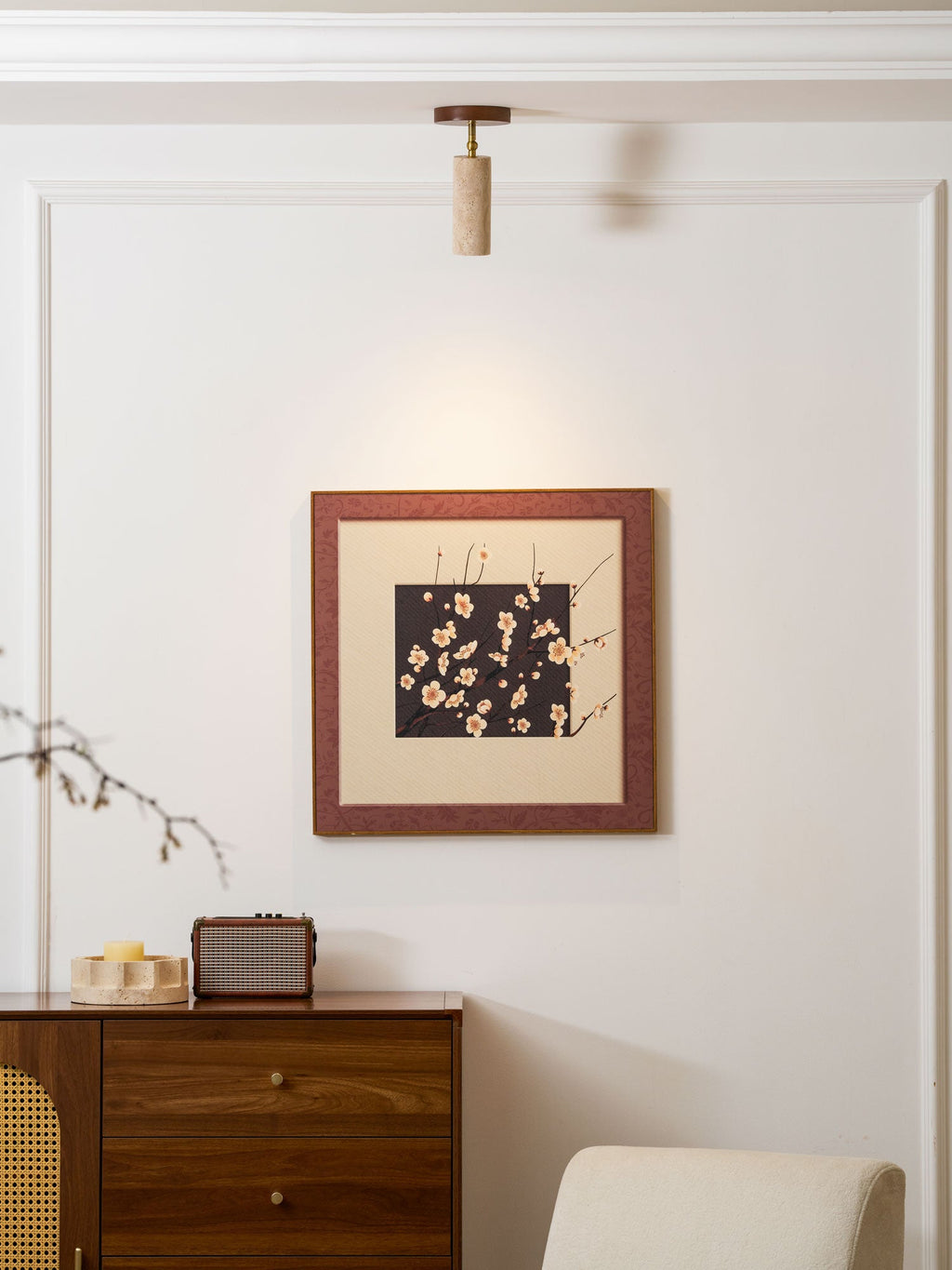 Clérachic stone spotlight above a framed blossom print, with a walnut sideboard, a retro speaker and a cream armchair below it.