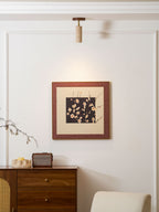 Clérachic stone spotlight above a framed blossom print, with a walnut sideboard, a retro speaker and a cream armchair below it.