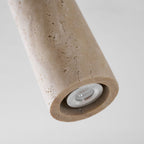 Close view of the pitted travertine surface and the open end of this Clérachic spotlight cylinder, with the small bulb inside.