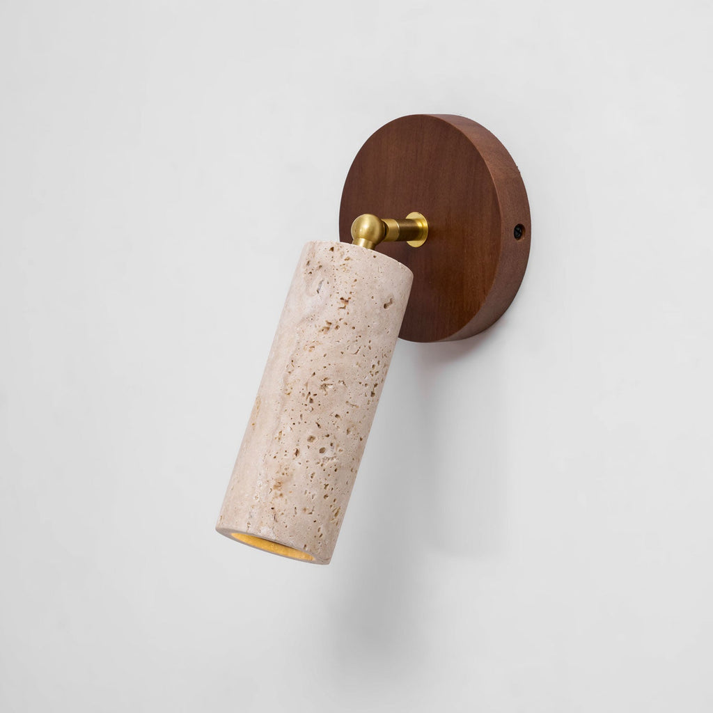Clérachic travertine spotlight on a white wall, hanging down from a brass swivel on a round walnut wall plate.
