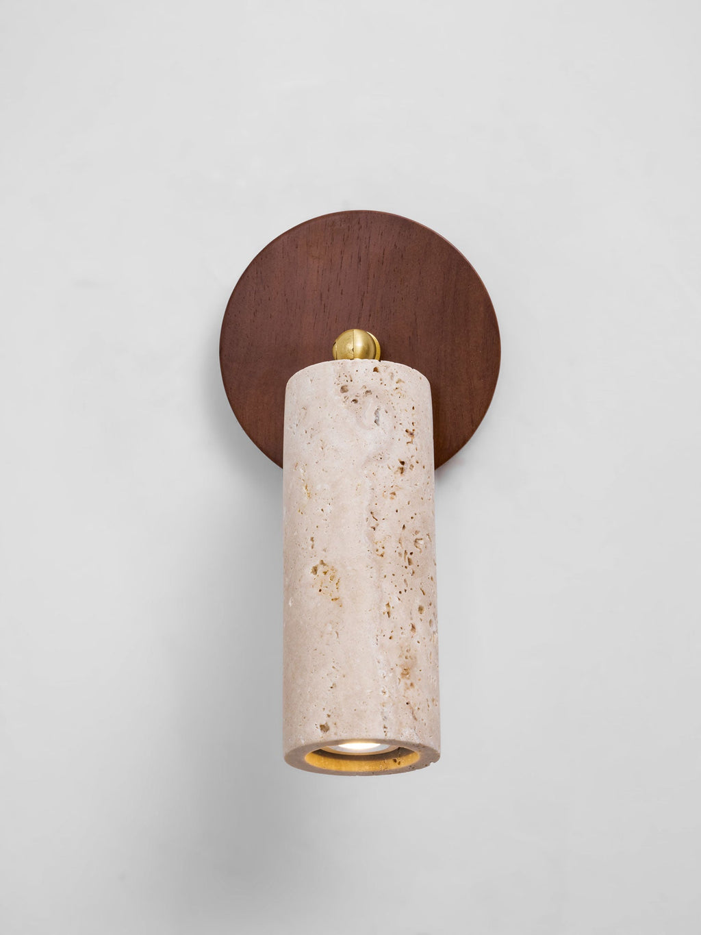 Front view of the Clérachic travertine spotlight pointing straight down from a round walnut wall plate on a white wall.